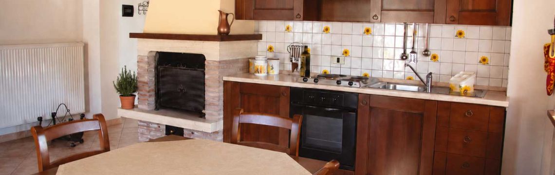 Cucina rustica con camino in agriturismo umbro, perfetta per un soggiorno accogliente e tipico.
